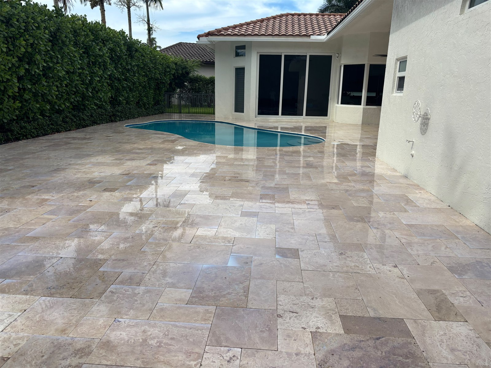 Clean stone pool deck beside a screened patio and swimming pool