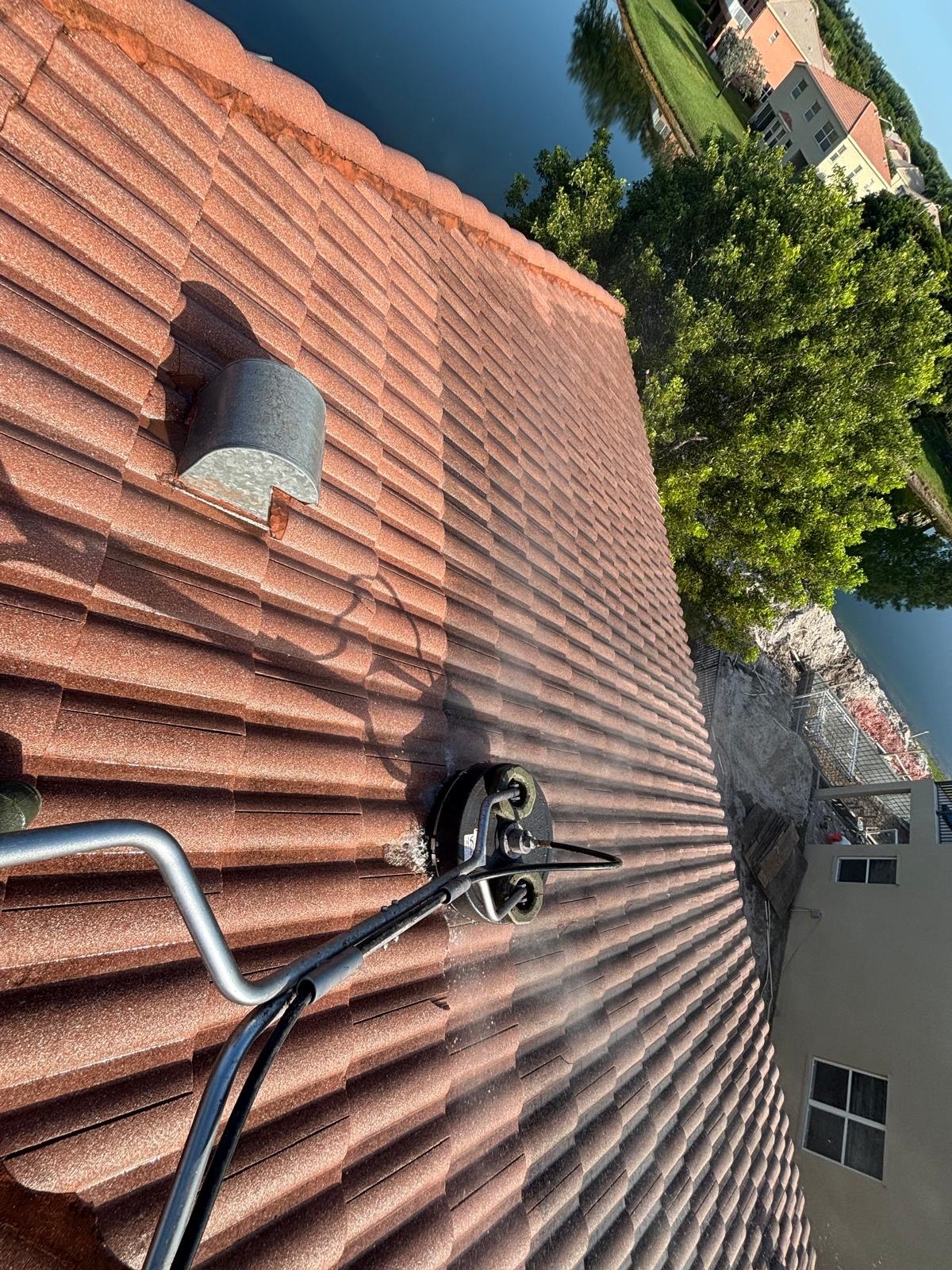 Cleaning equipment on a red tile roof beside a lake