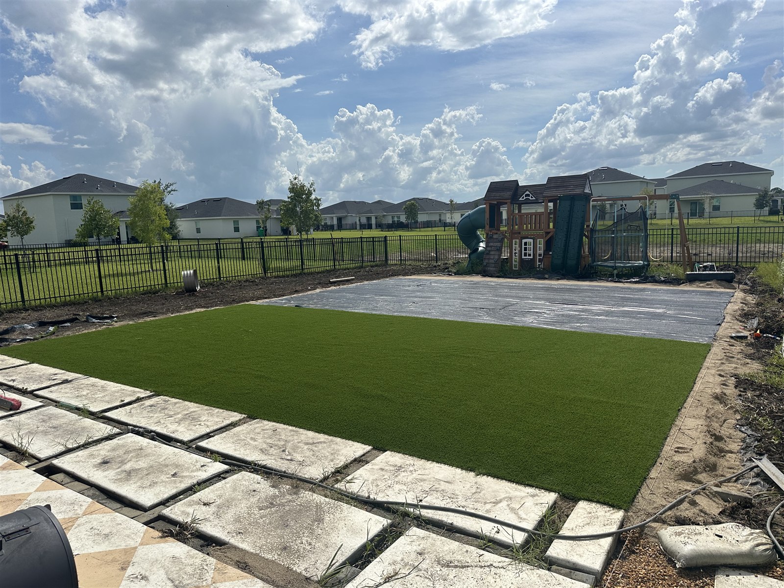 Turf installation, photo 2 of 4: first section of artificial turf laid beside the prepared ground covering